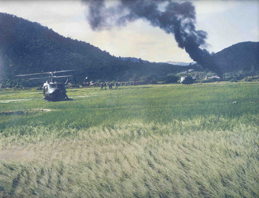 In the distance is a burning Huey; not
    one of ours.  Ed said a grunt accidentally detonated a grenade getting
    off the chopper, seriously wounding one of the pilots.