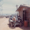 (07)  Unknown working on a jeep in front of avionics shop, motor pool in the background.